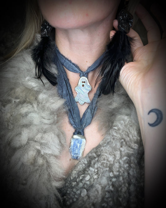 Small aura chalcedony ghost crystal carving with an iridescent glow in a sculptural silver-finish setting on dark gray recycled silk cords, handmade by Become Spellbound in Baltimore, Maryland.