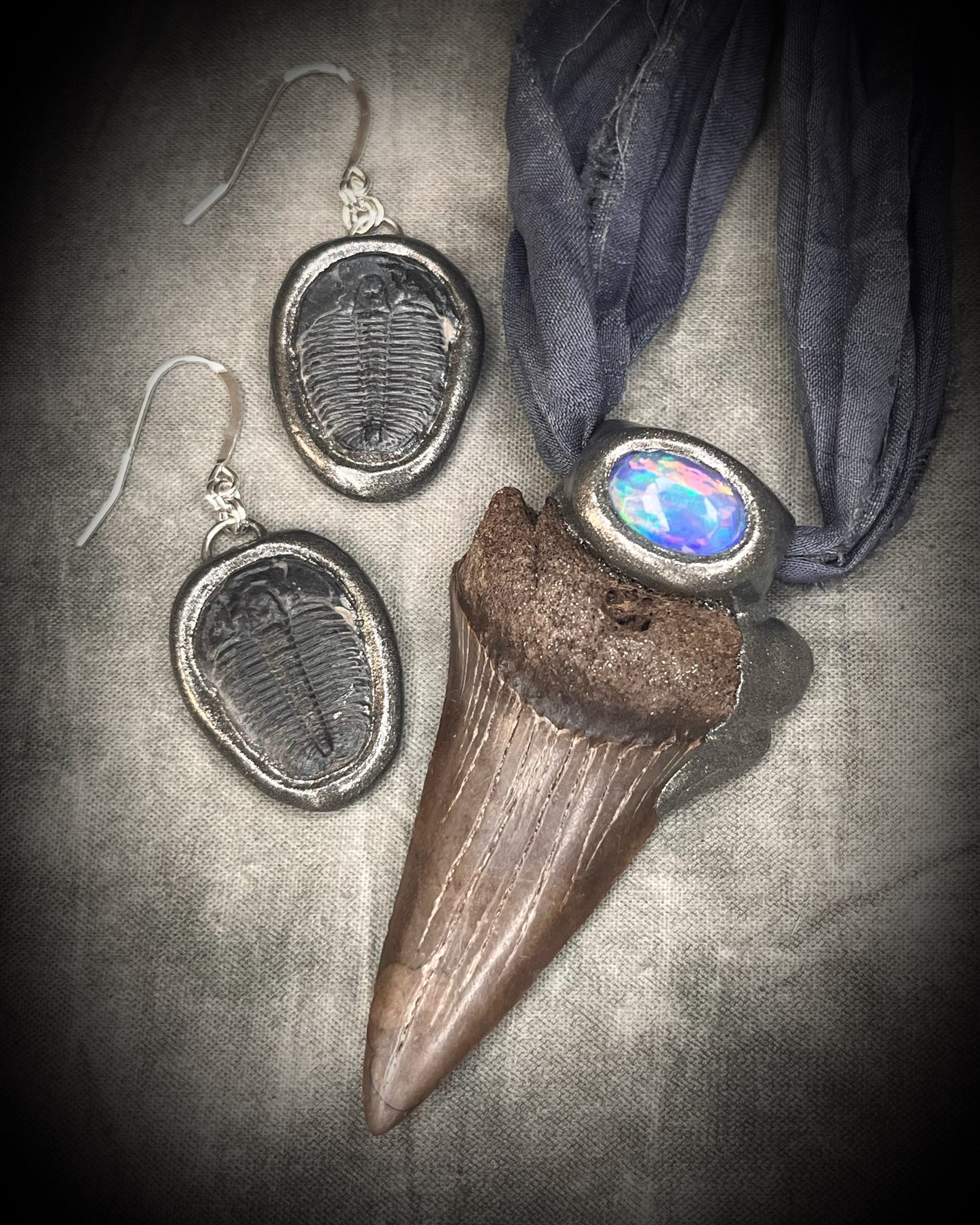 Trilobite Fossil Earrings in Gunmetal Silver Finish shown here with a Mako shark tooth and opal fossil pendant on grey recycled silk. 