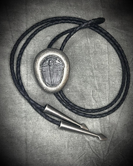 Trilobite fossil bolo tie with gunmetal finish, black leather, and dark silver bolo tips, handmade by Become Spellbound in Baltimore, Maryland.