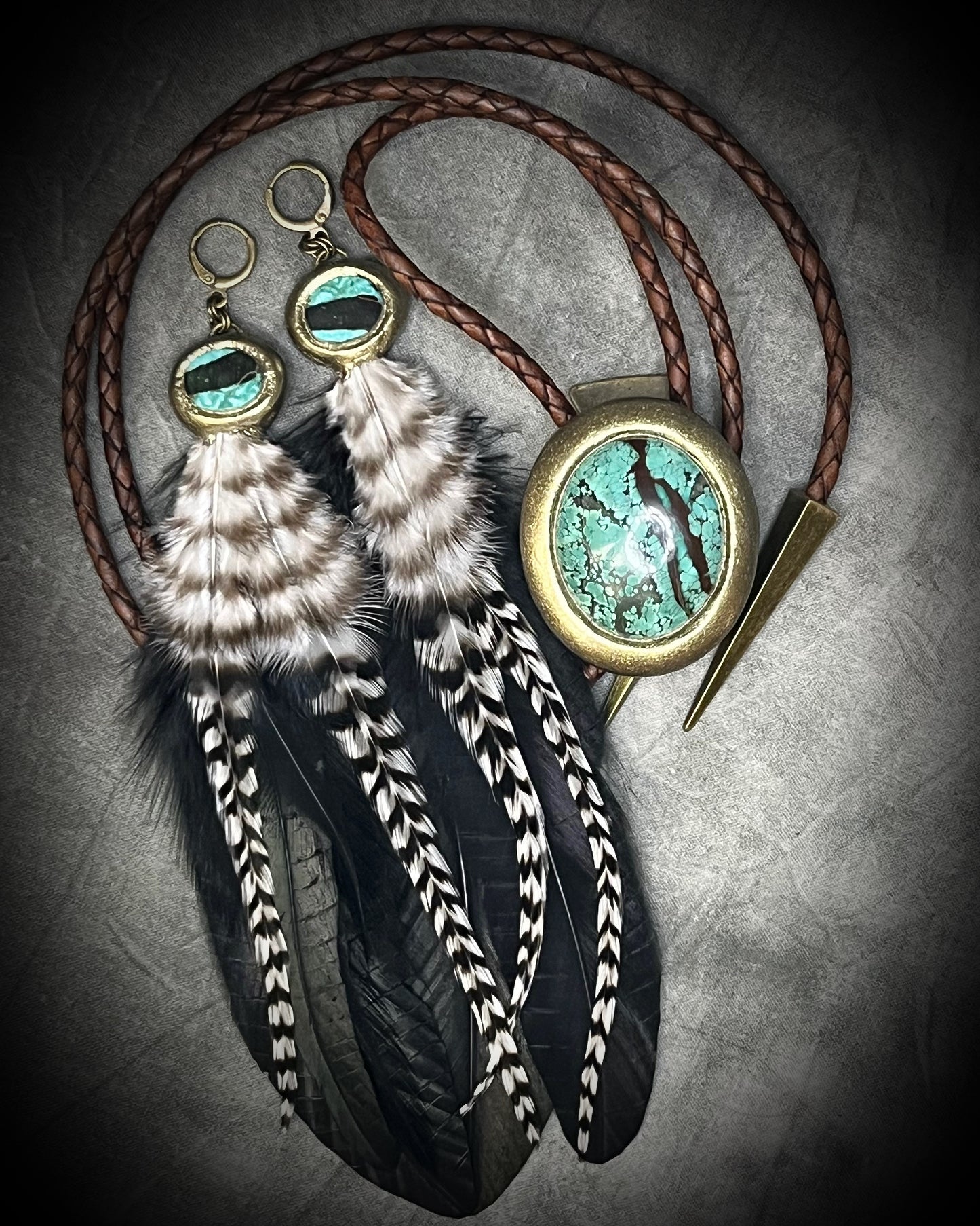Turquoise and feather earrings with natural blue-green stone, gold finish, and hypoallergenic brass huggie hooks, handmade by Become Spellbound. Shown here with Bolo tie as a set. 
