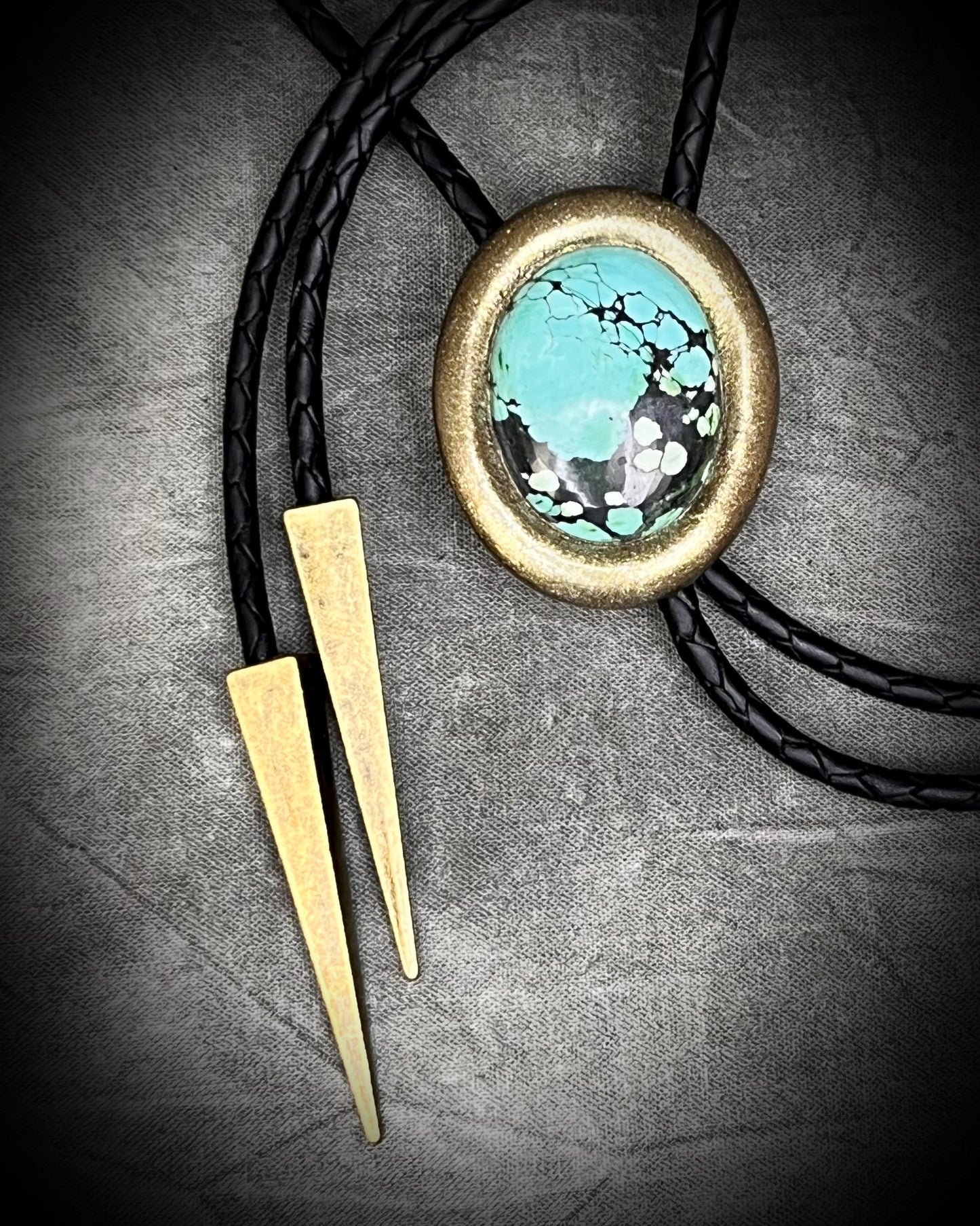 Turquoise bolo tie necklace in gold finish on black leather with spike tips, artisan Western statement jewelry with crystal focal stone, handmade in Baltimore Maryland.