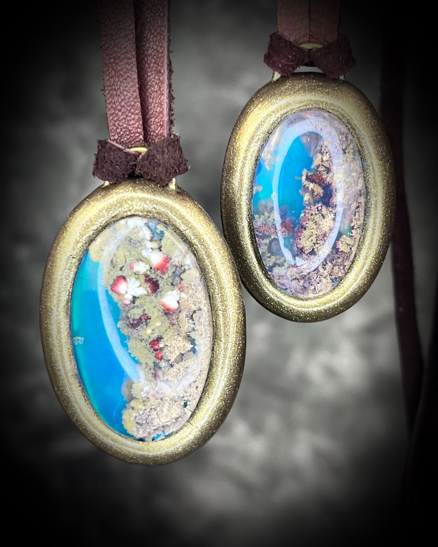 Two glowing, Scenic Moss Agate necklaces hung from earthy brown leather and styled against neutral linen background.