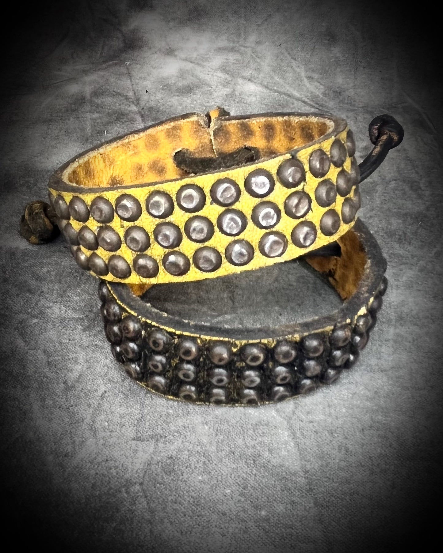 Two studded handmade leather bracelets worn layered on a wrist. Unisex rugged leather cuff jewelry.