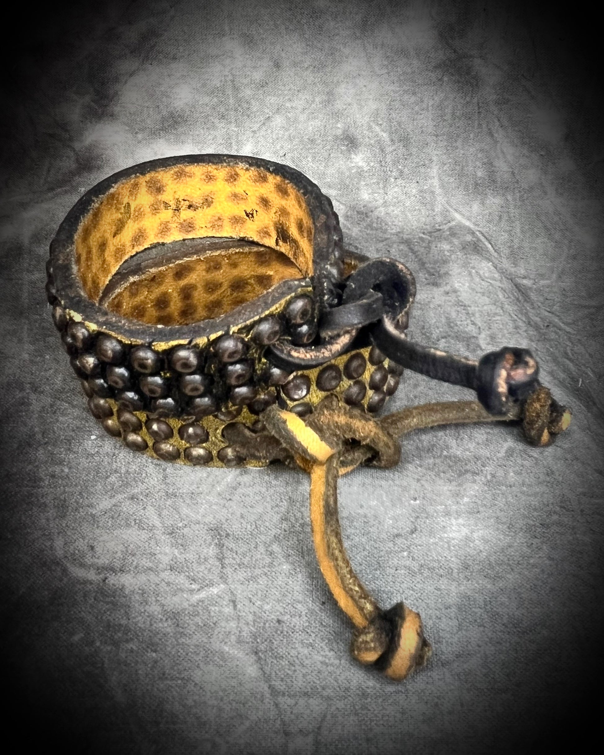 Two studded handmade leather bracelets worn layered on a wrist. Unisex rugged leather cuff jewelry shown here the tie back.