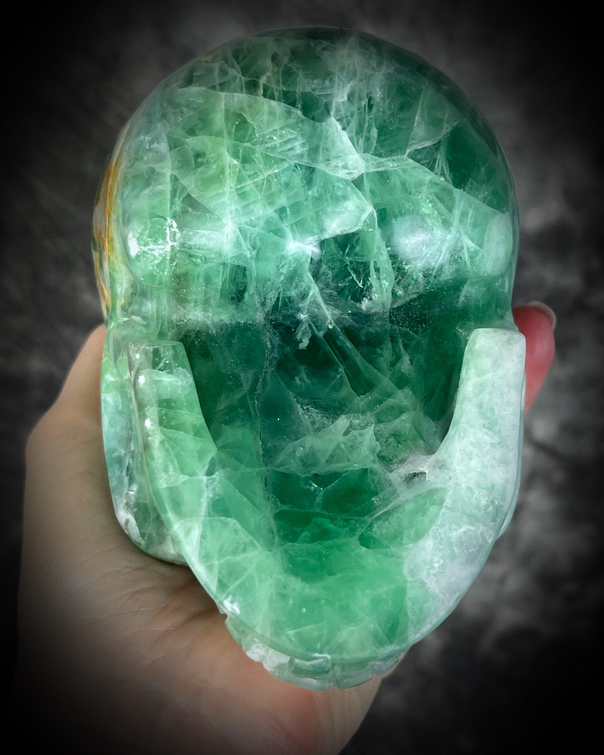 Underneath shot of  Large 5-inch green fluorite crystal skull with layered green bands and polished carved features.