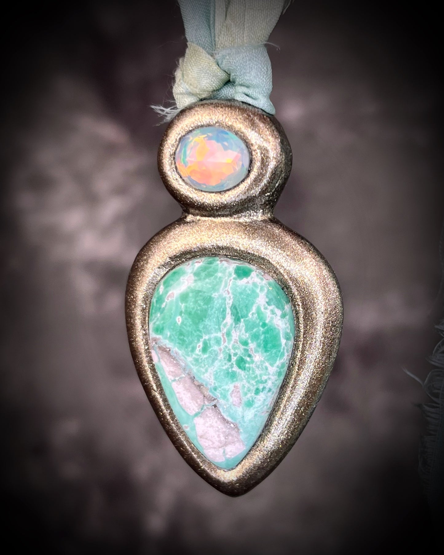 Variscite crystal pendant with green and white stone adorned with a sparkling opal and crafted in a gold frame. Gold necklace hung from soft sea green recycled silk. Boho Spiritual jewelry gift for her. 