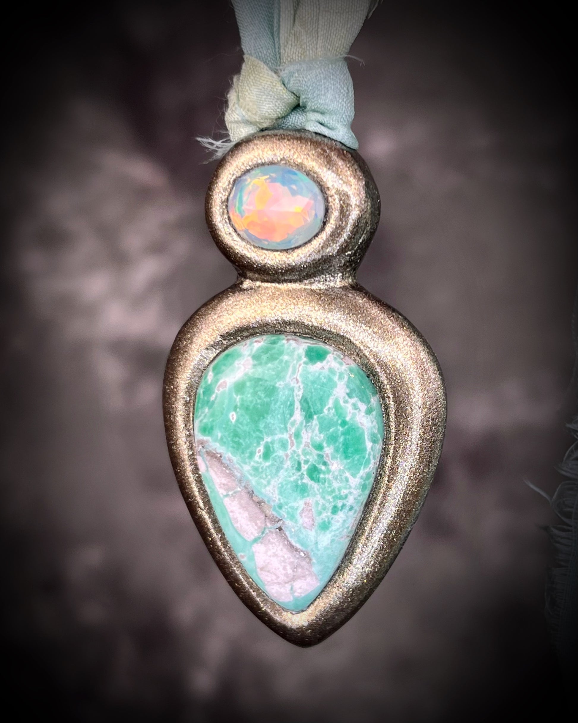 Variscite crystal pendant with green and white stone adorned with a sparkling opal and crafted in a gold frame. Gold necklace hung from soft sea green recycled silk. Boho Spiritual jewelry gift for her. 