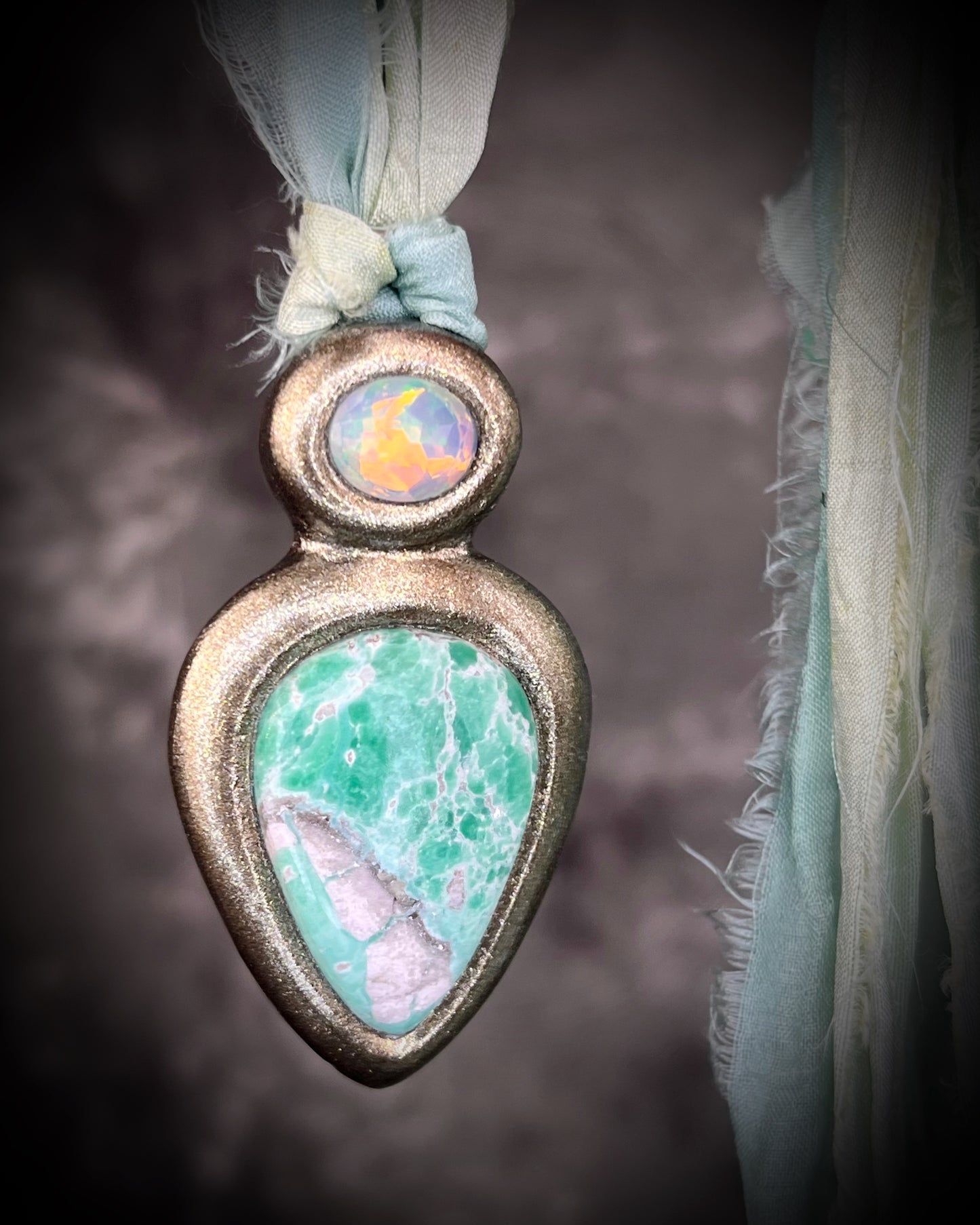 Variscite crystal pendant with green and white stone adorned with a sparkling opal and crafted in a gold frame. Gold necklace hung from soft sea green recycled silk. Boho Spiritual jewelry gift for her. 