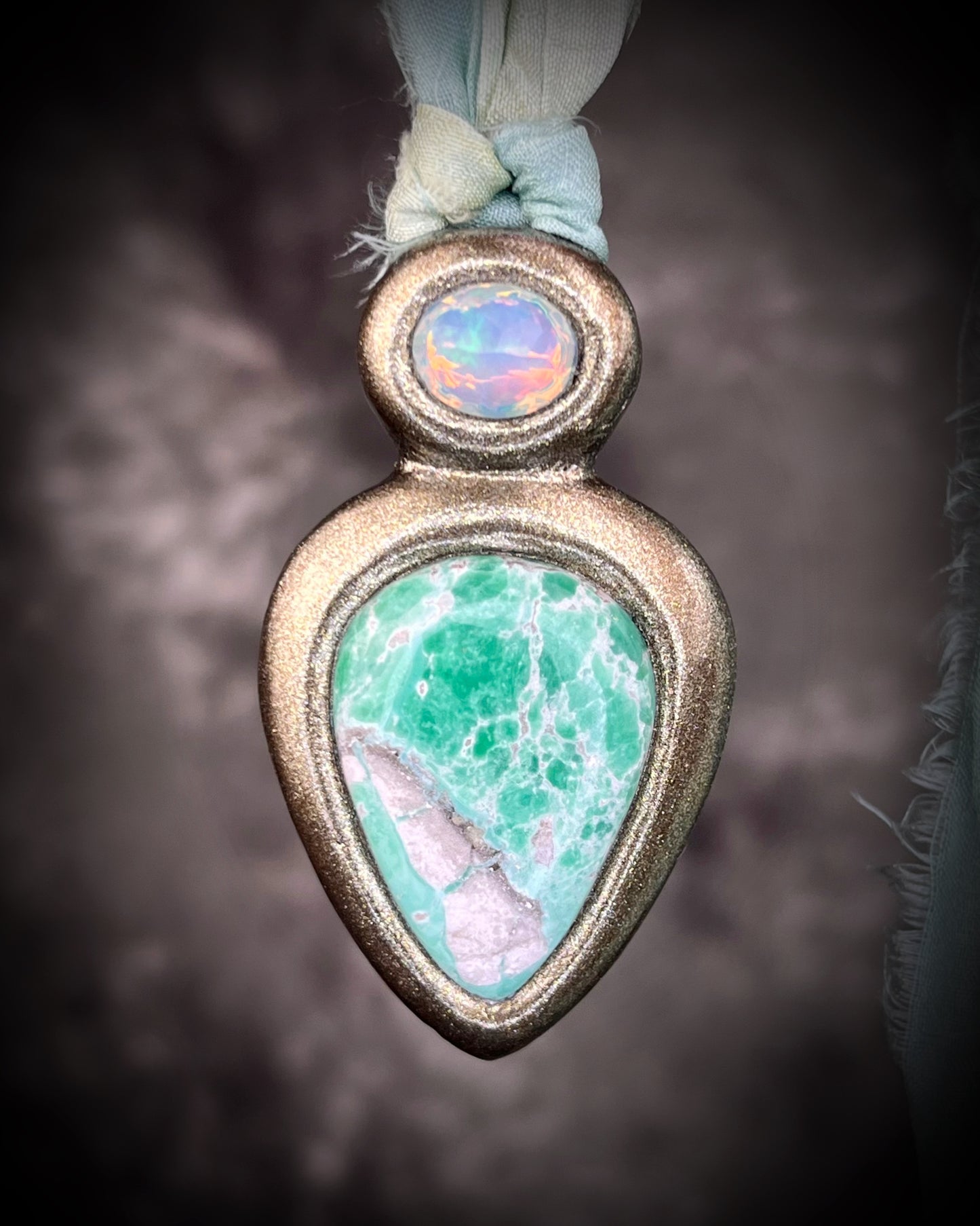 Variscite crystal pendant with green and white stone adorned with a sparkling opal and crafted in a gold frame. Gold necklace hung from soft sea green recycled silk. Boho Spiritual jewelry gift for her. 