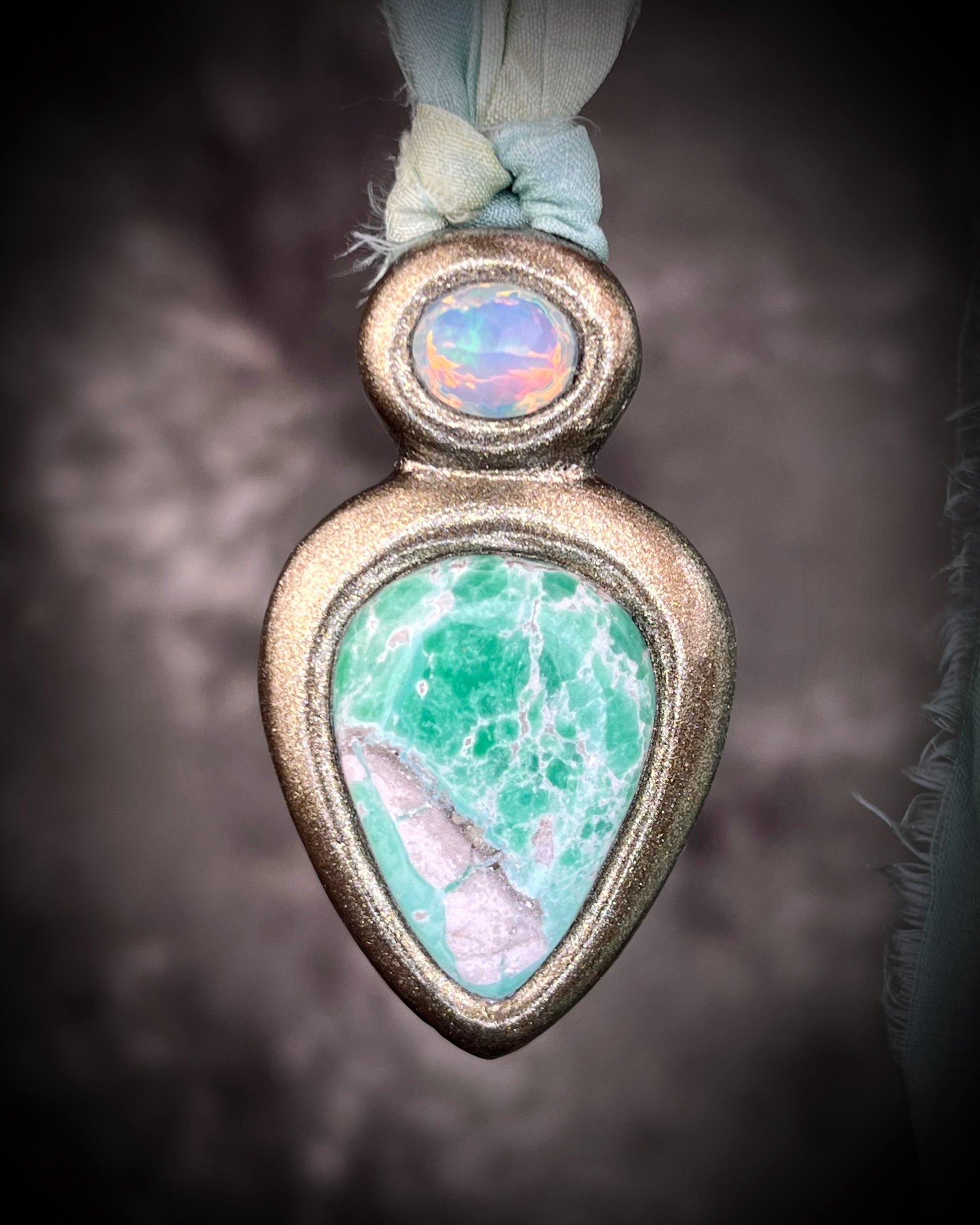 Variscite crystal pendant with green and white stone adorned with a sparkling opal and crafted in a gold frame. Gold necklace hung from soft sea green recycled silk. Boho Spiritual jewelry gift for her. 