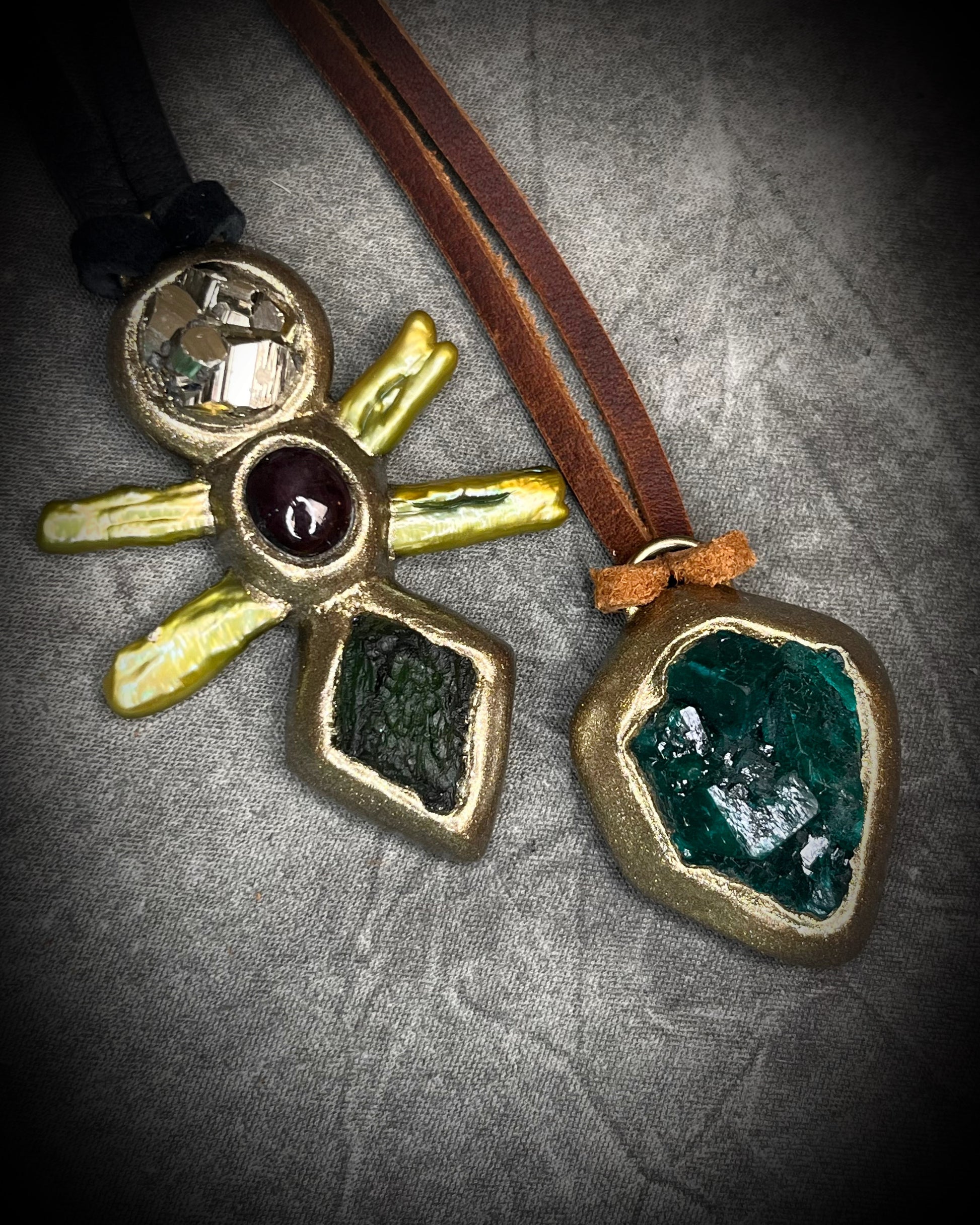 Vivid emerald green chunky dioptase crystal pendant handmade and set in a gold finish, hung from soft brown leather for an earthy, unisex vibe. Jewery for men or gift for her. Shown here with moldavite talisman.