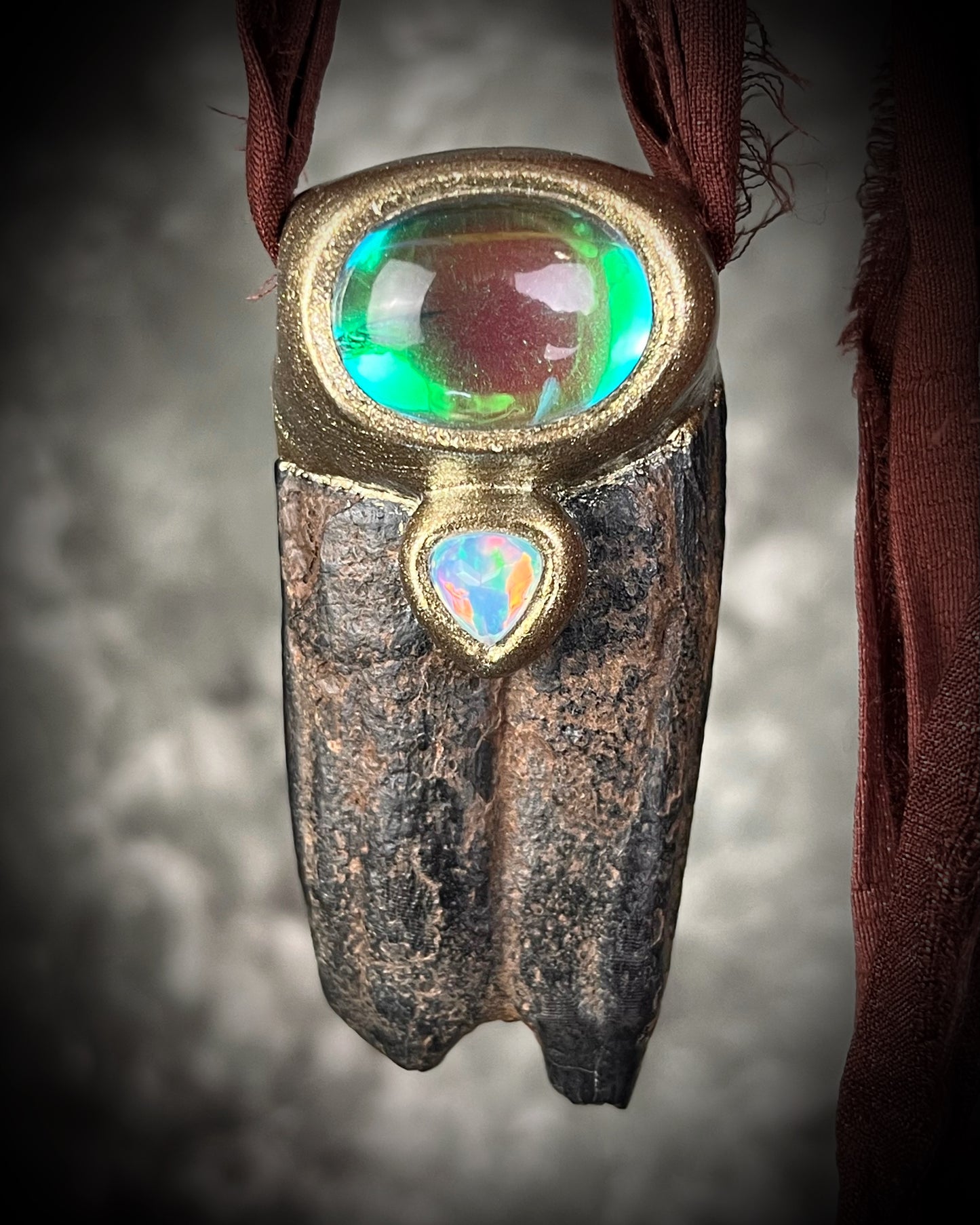 Western Style 'Year of the Horse 2026' inspired horse tooth fossil necklace with glowing green fluorite crystal and fiery opal gemstone. Gold finish horse necklace with brown recycled silk for an earthy and grounded talisman for her.