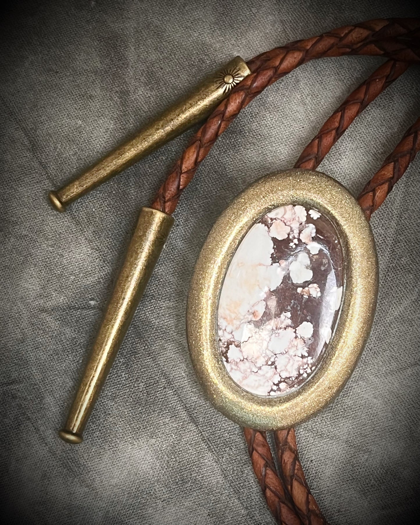 Wild Horse magnesite bolo tie with gold finish on brown leather cord, earthy Western statement jewelry featuring natural patterned stone, handmade bolo tie necklace Baltimore Maryland