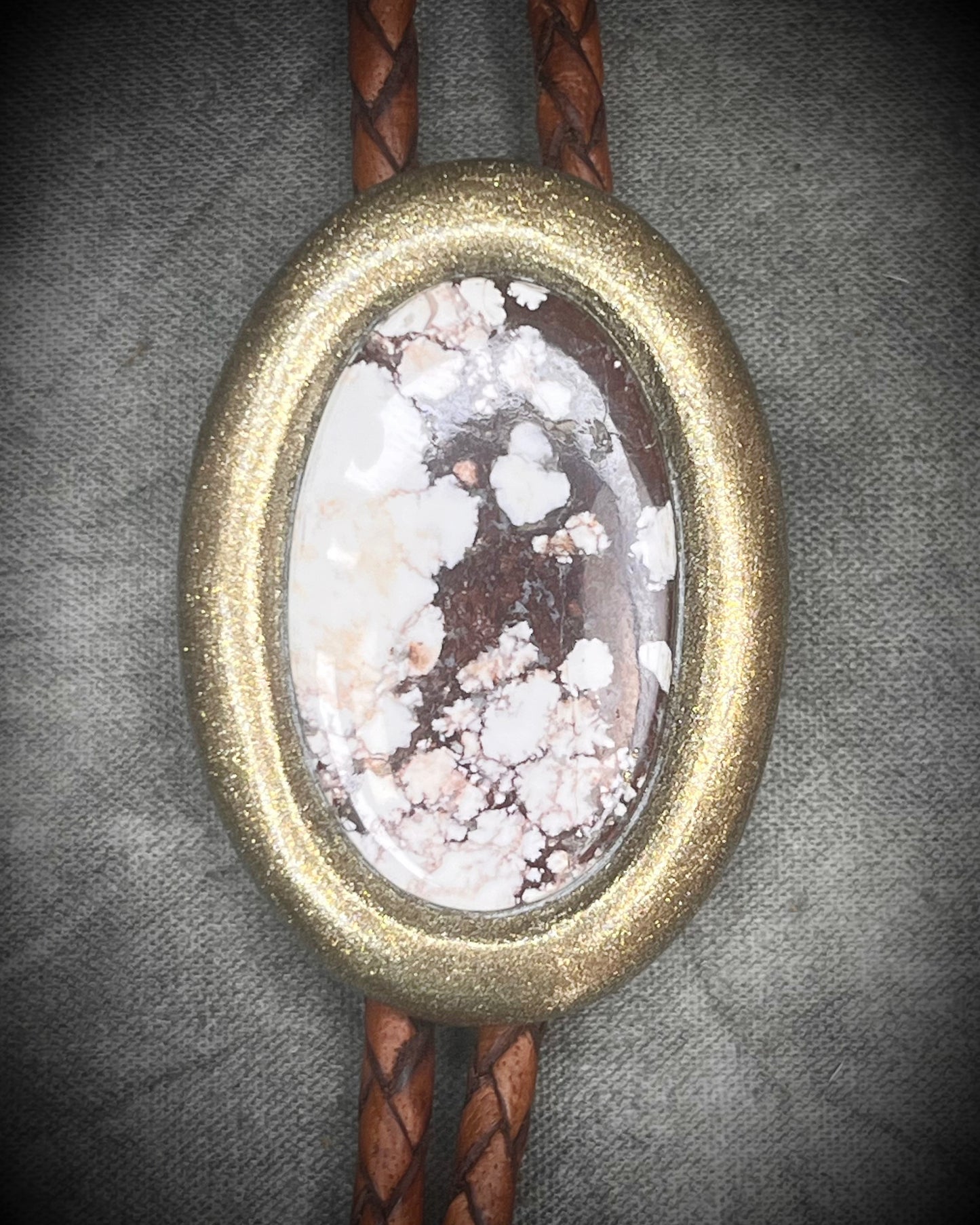 Wild Horse magnesite bolo tie with gold finish on brown leather cord, earthy Western statement jewelry featuring natural patterned stone, handmade bolo tie necklace Baltimore Maryland