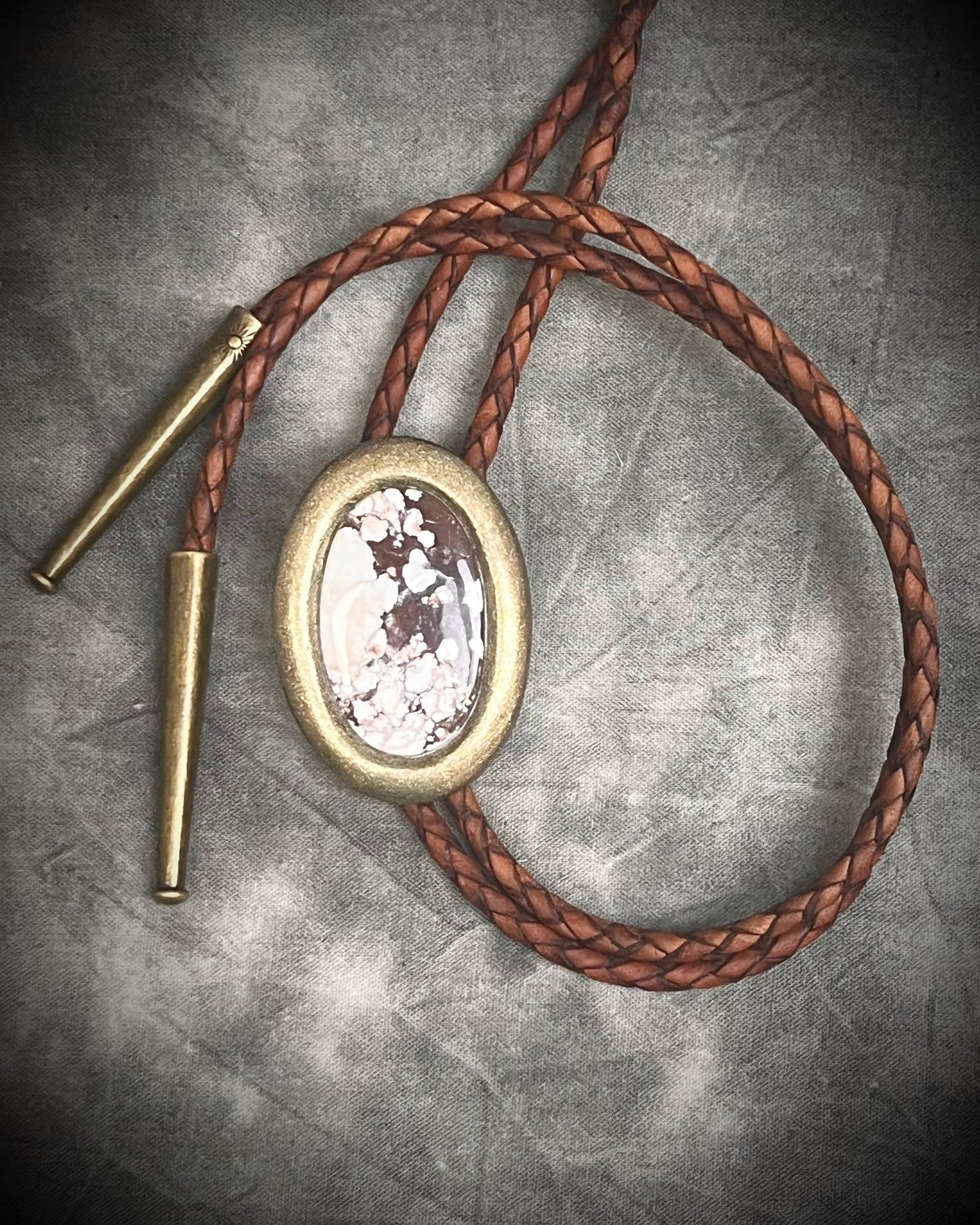 Wild Horse magnesite bolo tie with gold finish on brown leather cord, earthy Western statement jewelry featuring natural patterned stone, handmade bolo tie necklace Baltimore Maryland