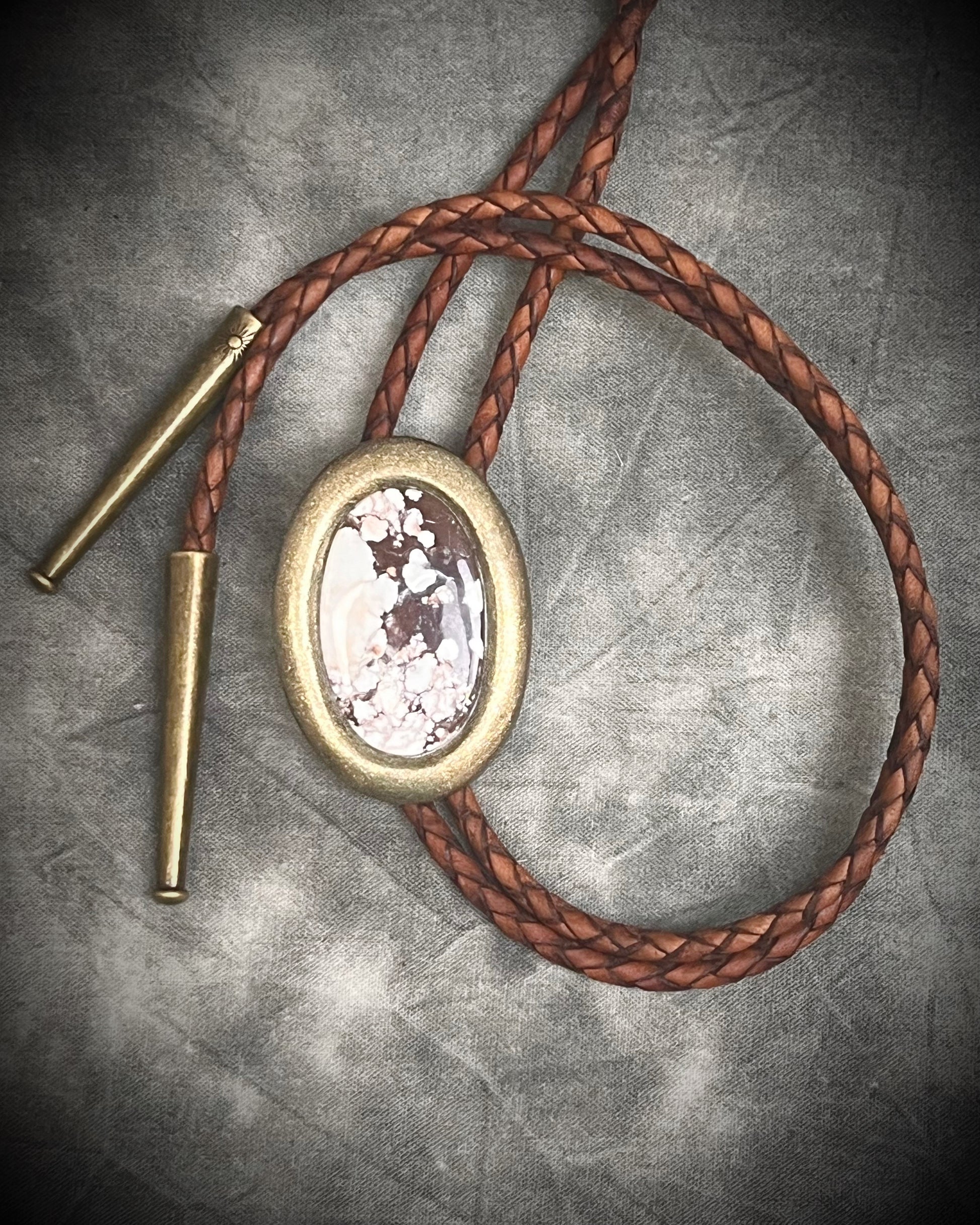 Wild Horse magnesite bolo tie with gold finish on brown leather cord, earthy Western statement jewelry featuring natural patterned stone, handmade bolo tie necklace Baltimore Maryland