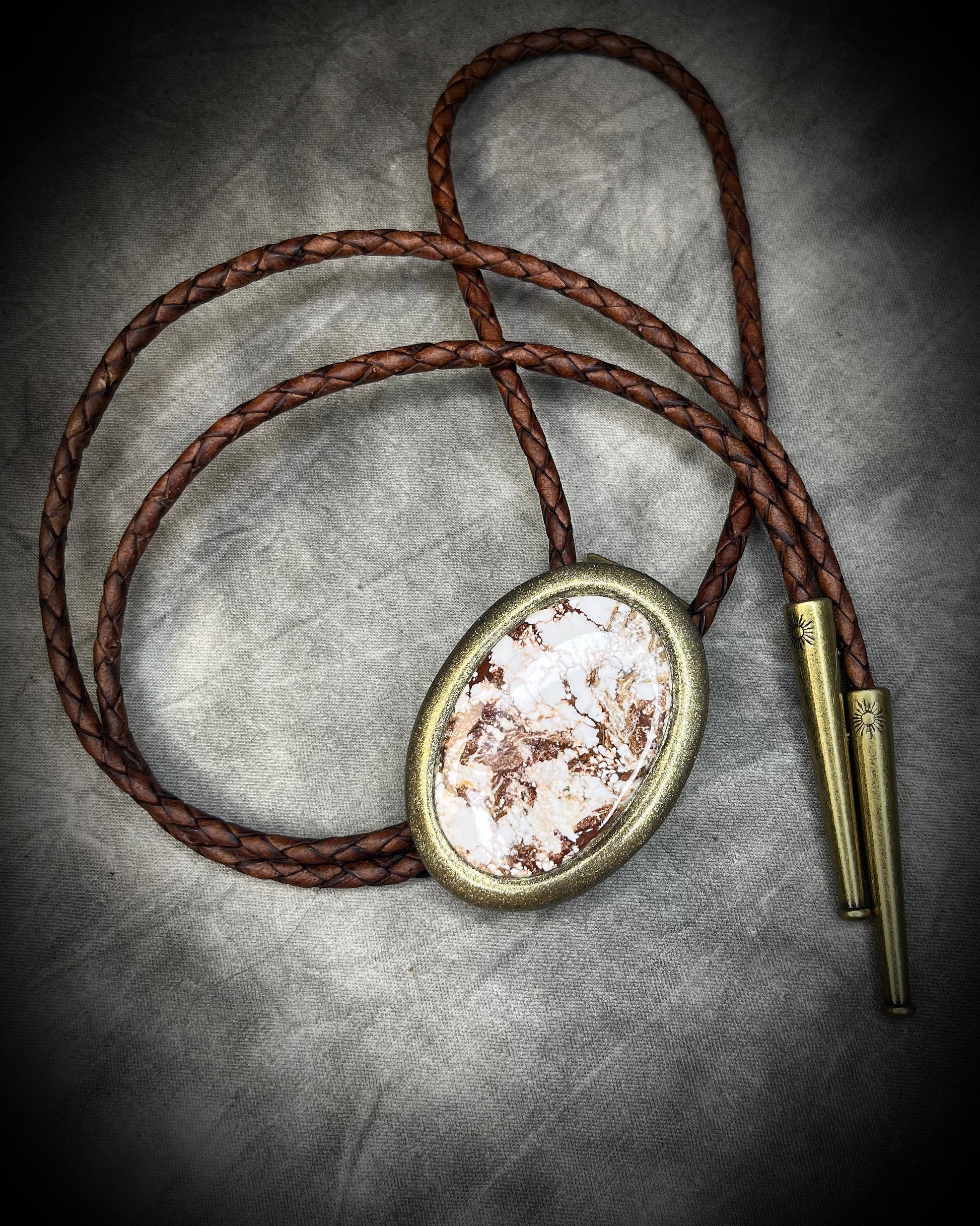 Wild Horse magnesite bolo tie with natural cream and brown markings, brown leather, gold finish, and gold bolo tips.