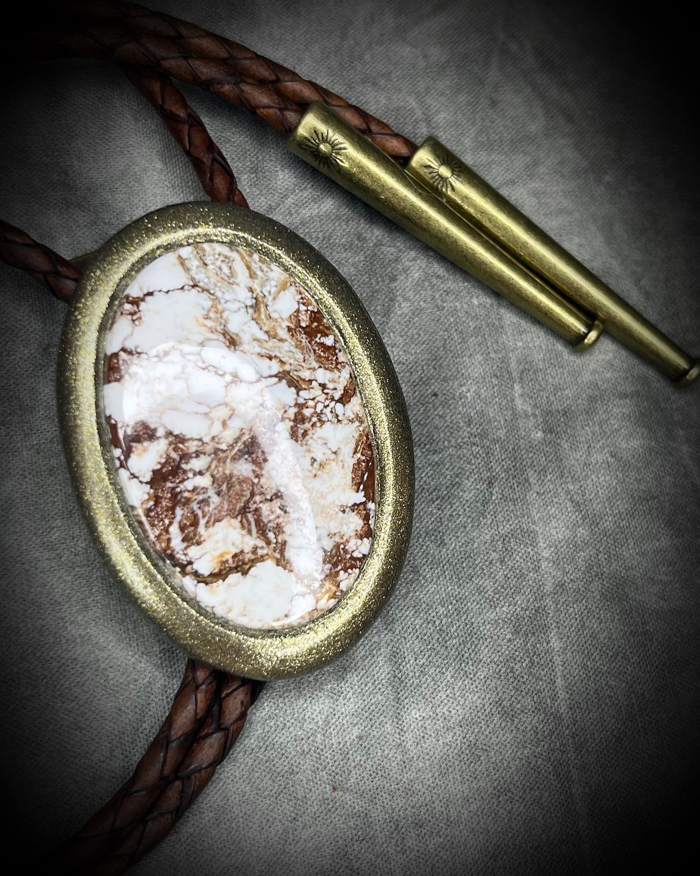Wild Horse magnesite bolo tie with natural cream and brown markings, brown leather, gold finish, and gold bolo tips.