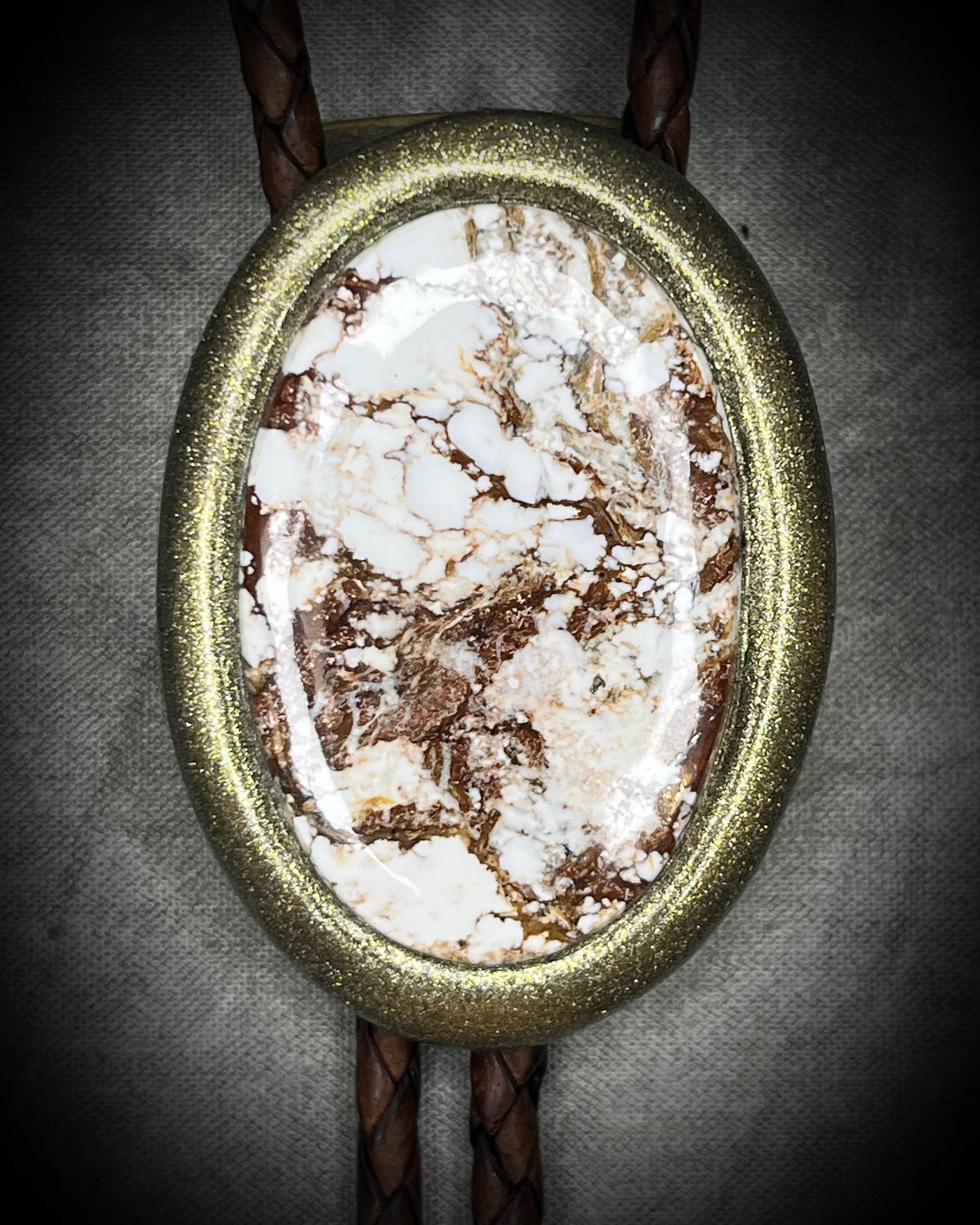 Wild Horse magnesite bolo tie with natural cream and brown markings, brown leather, gold finish, and gold bolo tips.