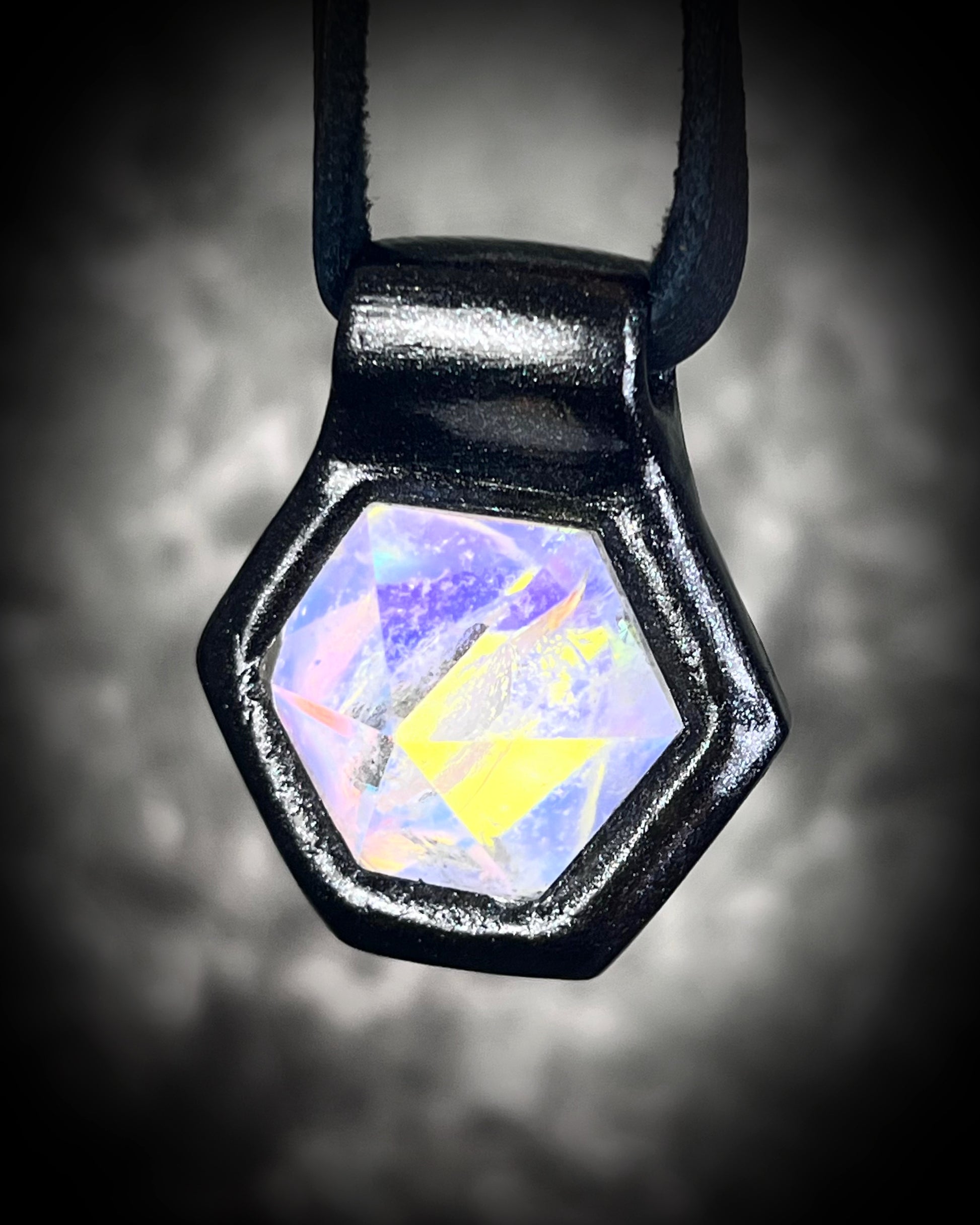 Witchy opalescent quartz crystal pendant framed in black, spiritual necklace on leather cord, gothic statement jewelry for Halloween and mystical style.