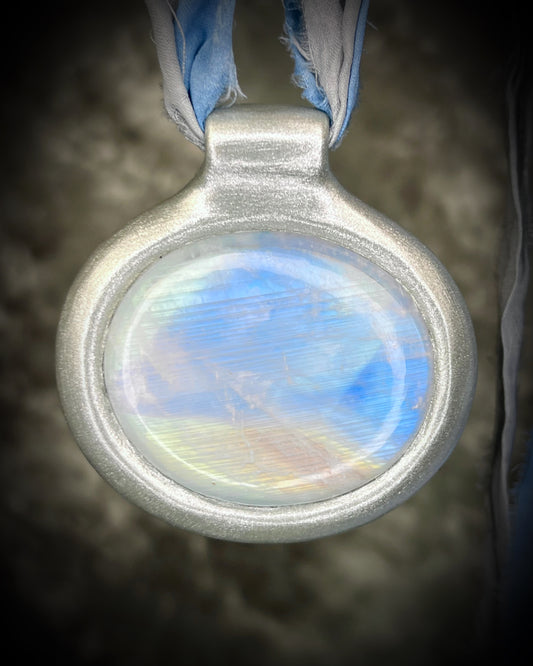 XL rainbow moonstone fire pendant handmade in a silver finish for moon goddess energy. Hung from blue and silver recycled silk for an ethereal and intuitive energy. Spiritual summer jewelry gift for her. 