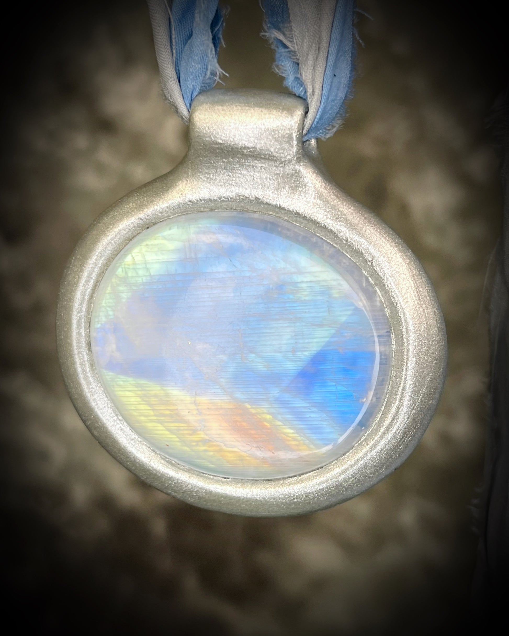 XL rainbow moonstone fire pendant handmade in a silver finish for moon goddess energy. Hung from blue and silver recycled silk for an ethereal and intuitive energy. Spiritual summer jewelry gift for her. 