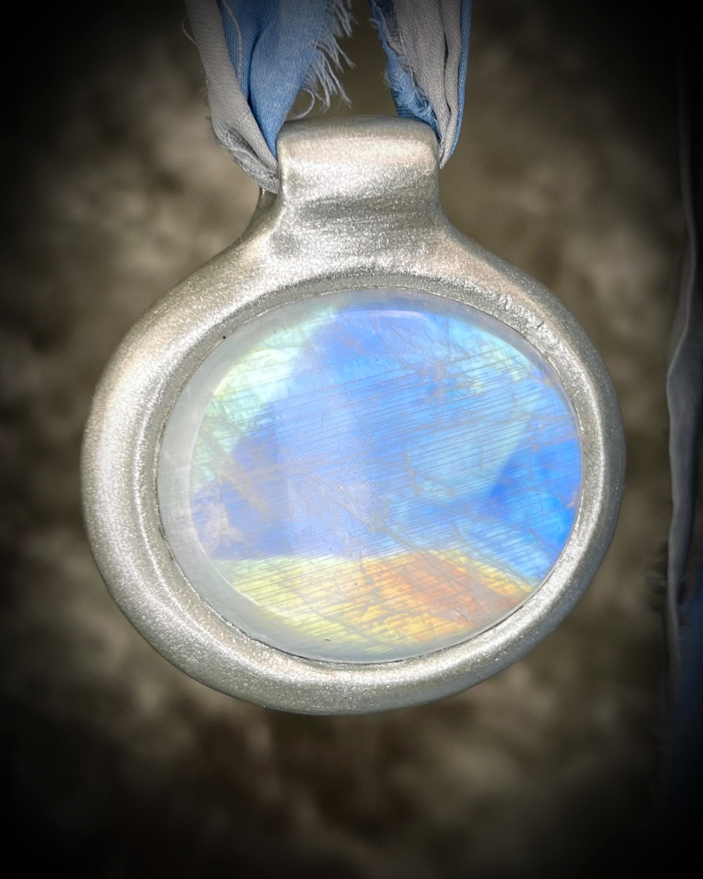 XL rainbow moonstone fire pendant handmade in a silver finish for moon goddess energy. Hung from blue and silver recycled silk for an ethereal and intuitive energy. Spiritual summer jewelry gift for her. 