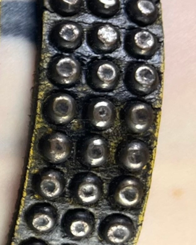 closeup of distressed earthy brown leather studded bracelet. 