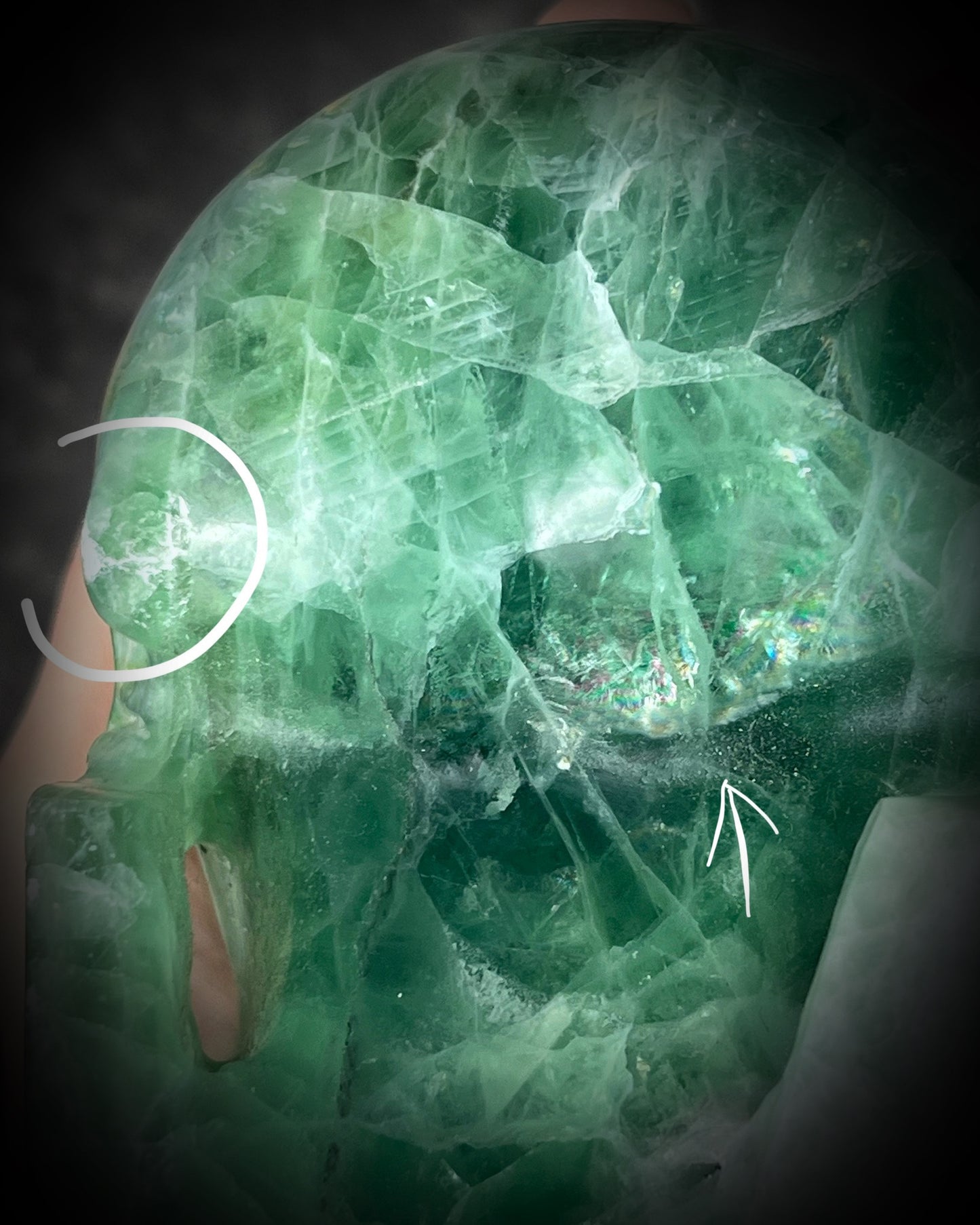 Close-up of a green crystal with visible cracks and imperfections.