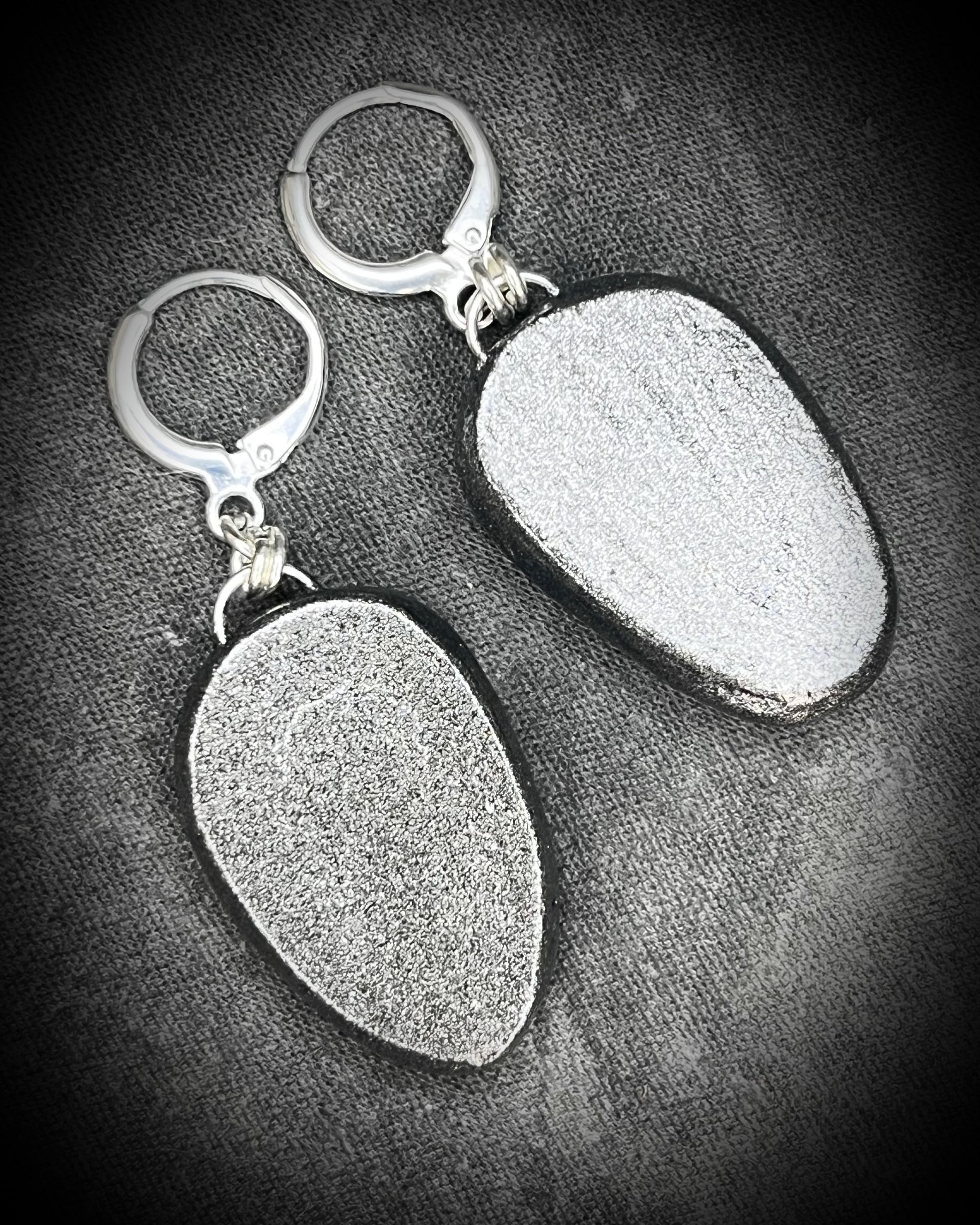 Pair of silver  handmade earrings with hematite protection stones on a textured gray background
