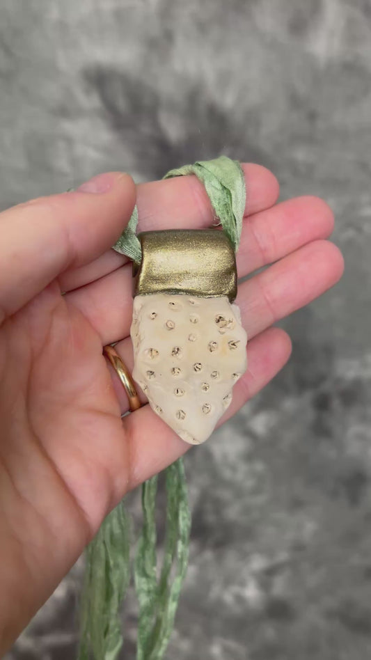 Genuine fossil coral set in a gold setting and hung from sea green recycled silks as a beachy oceanic summer jewelry look. Necklace handmade in Baltimore with coral from Calvert Cliffs.