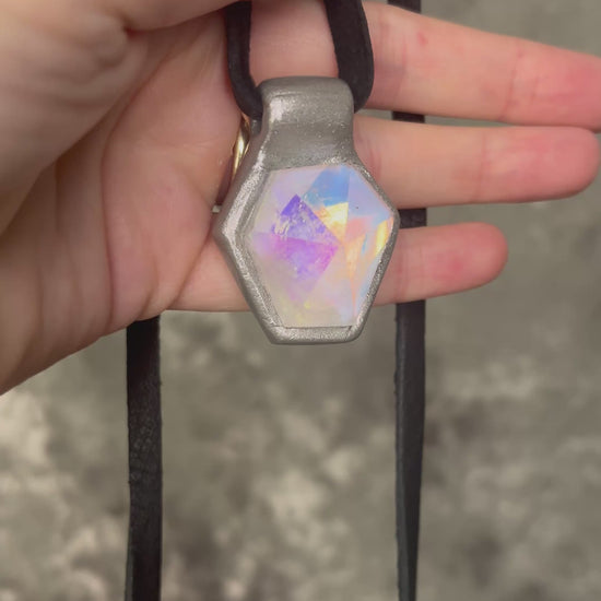 Handmade clear quartz crystal necklace with an opalescent flash that feels enchanted from another realm. Framed in silver in a hexagon shape and hung from black leather, this pendant feels cinematic, and like an unearthed treasure. 