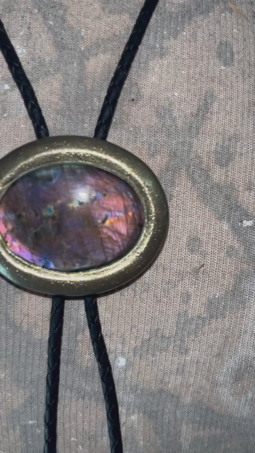 Necklace with a bolo tie design featuring a colorful purple labradorite stone pendant on a male bust. Gold finish bolo tie with black leather, holiday gift for him.