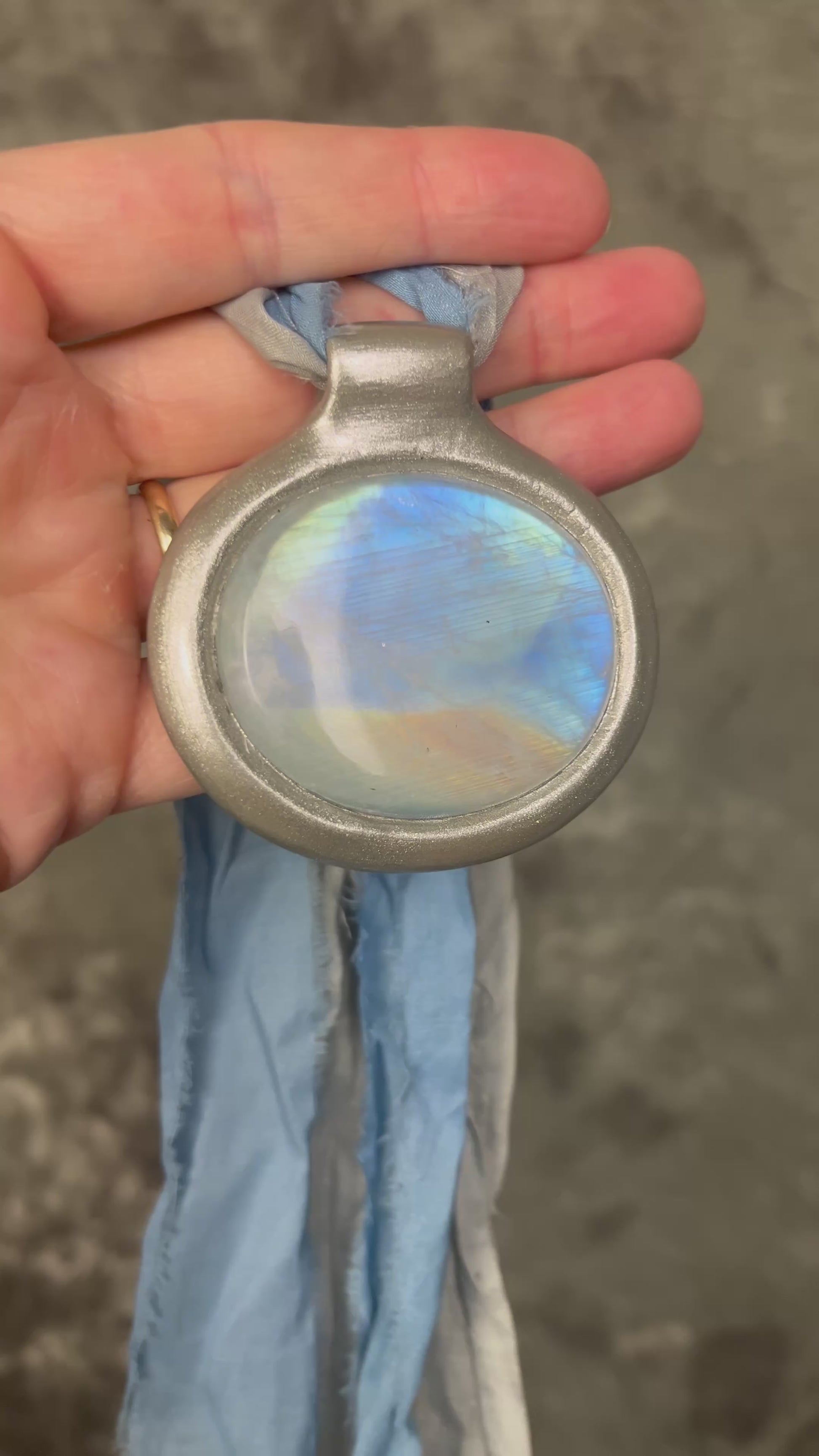 XL rainbow moonstone fire pendant handmade in a silver finish for moon goddess energy. Hung from blue and silver recycled silk for an ethereal and intuitive energy. Spiritual summer jewelry gift for her. 