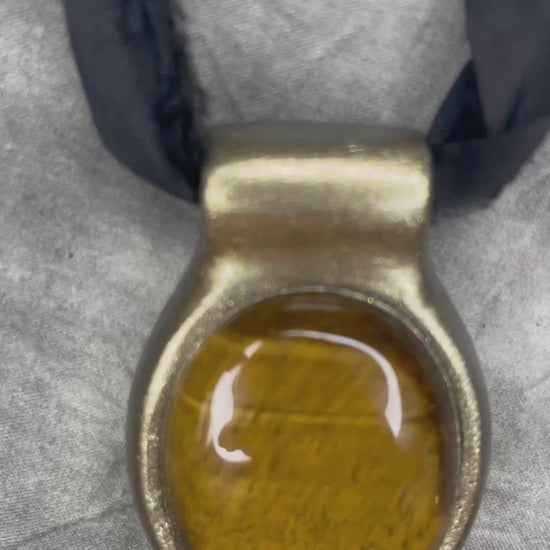 Extra large tiger's eye crystal talisman with golden-brown natural banding, gold finish, and black recycled silk ties, handmade by Become Spellbound in Baltimore, Maryland.