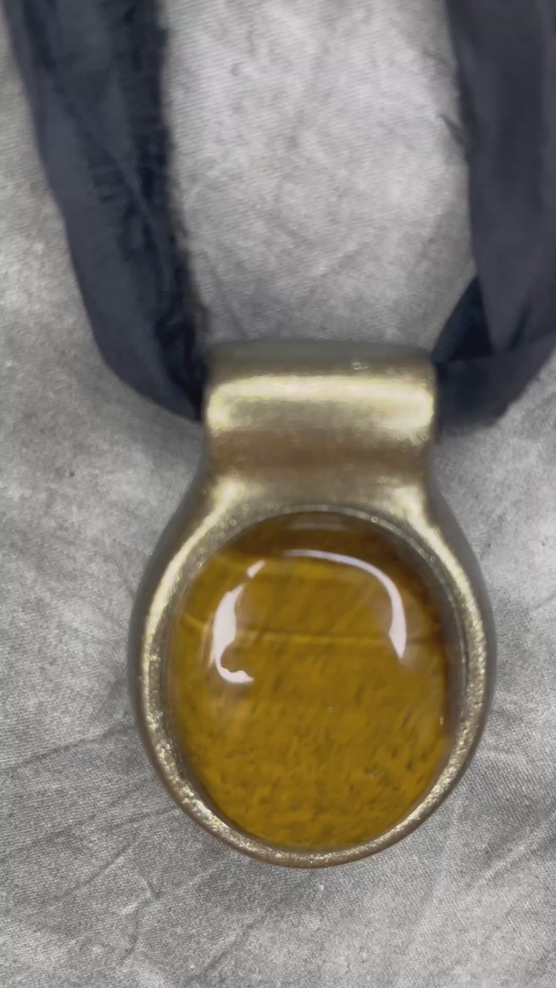 Extra large tiger's eye crystal talisman with golden-brown natural banding, gold finish, and black recycled silk ties, handmade by Become Spellbound in Baltimore, Maryland.