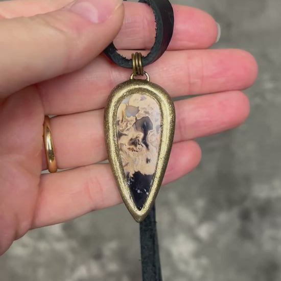 Petrified palm root necklace, teardrop shaped and set in a gold finish. Fossilized wood pendant hung from black leather for a protective and grounding vibe. 