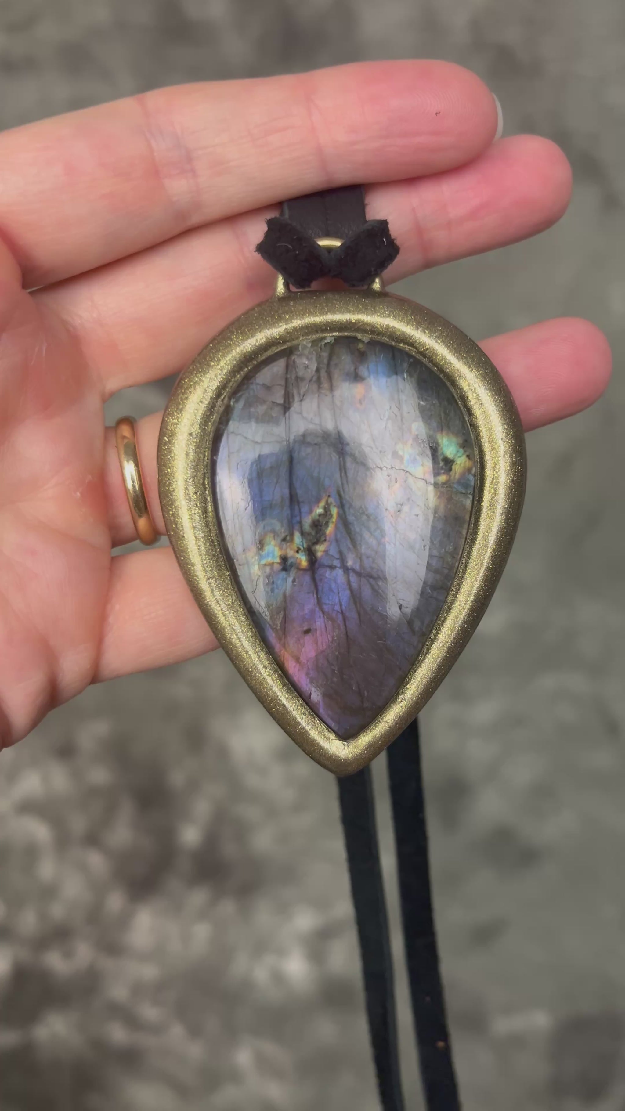 Purple flash moody violet labradorite teardrop crystal necklace in a gold finish on black leather. Handmade mystical jewelry statement pendant for her. 