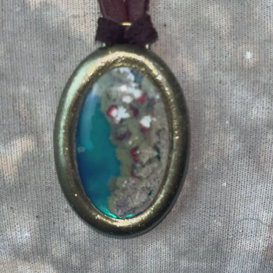Close-up video of mossy green, pink and ivory inclusions within aqua translucent agate crystal necklaces.