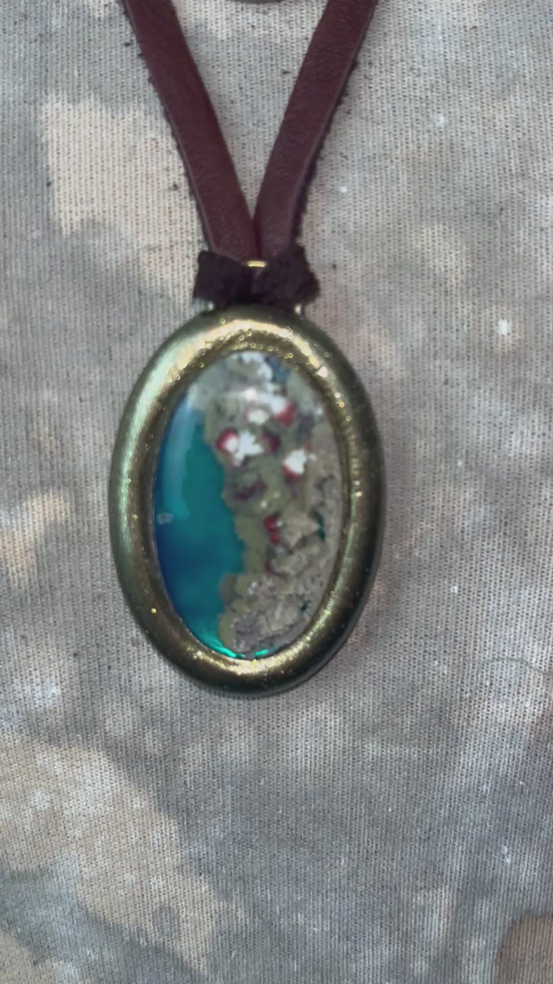Close-up video of mossy green, pink and ivory inclusions within aqua translucent agate crystal necklaces.