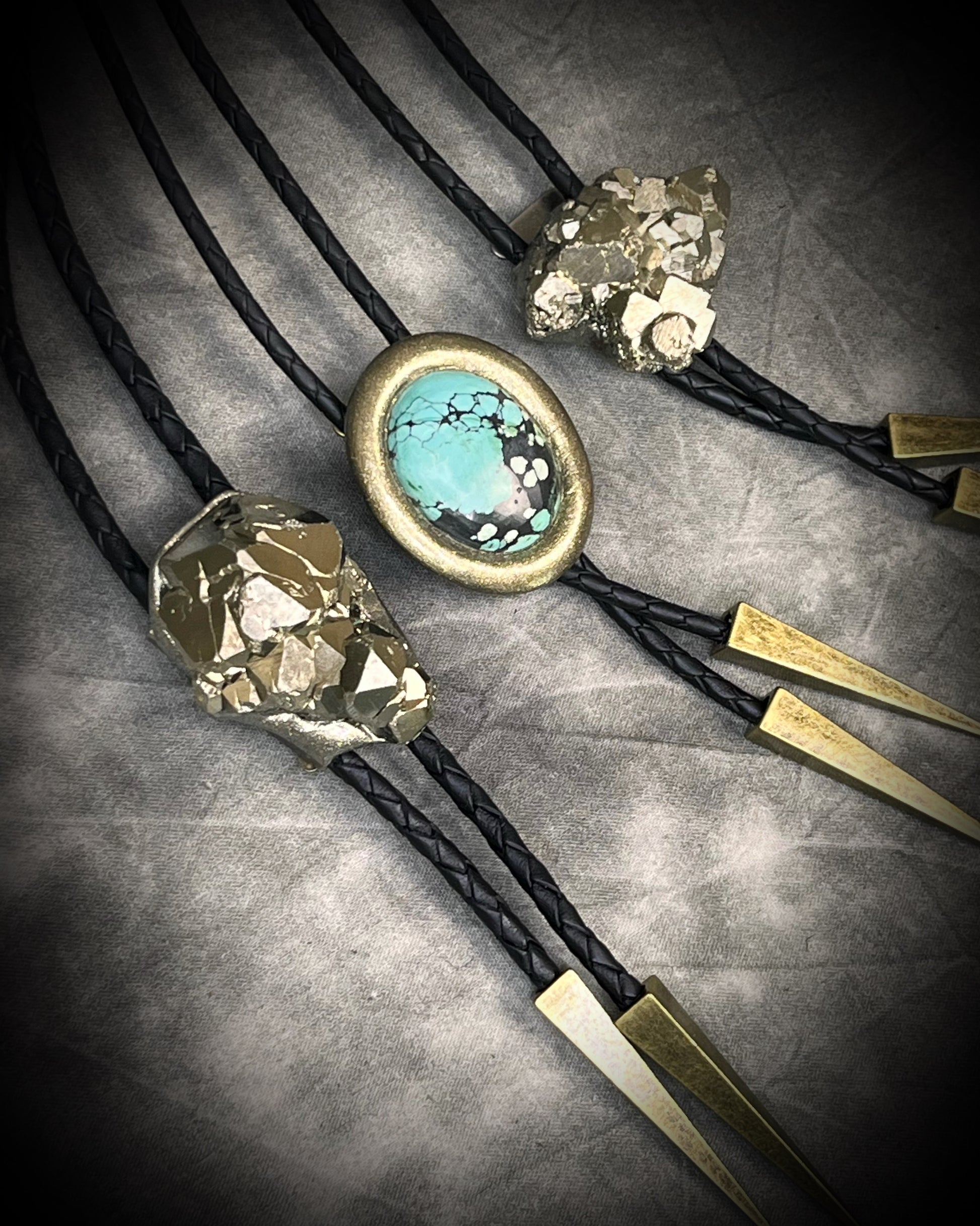 Bolo tie with turquoise stone and gold accents on a gray surface
