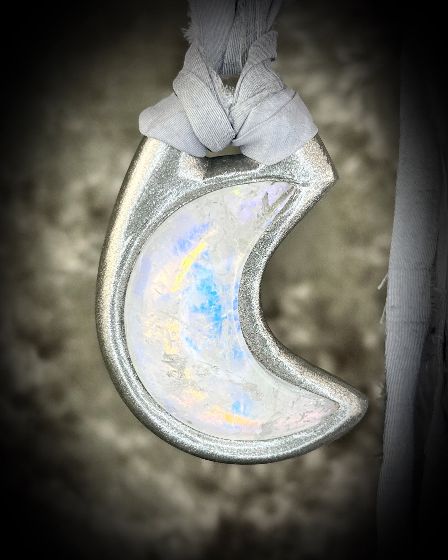 Handcrafted designer opalescent quartz gemstone crescent moon pendant in a silver finish with sustainable festival style recycled silks. 